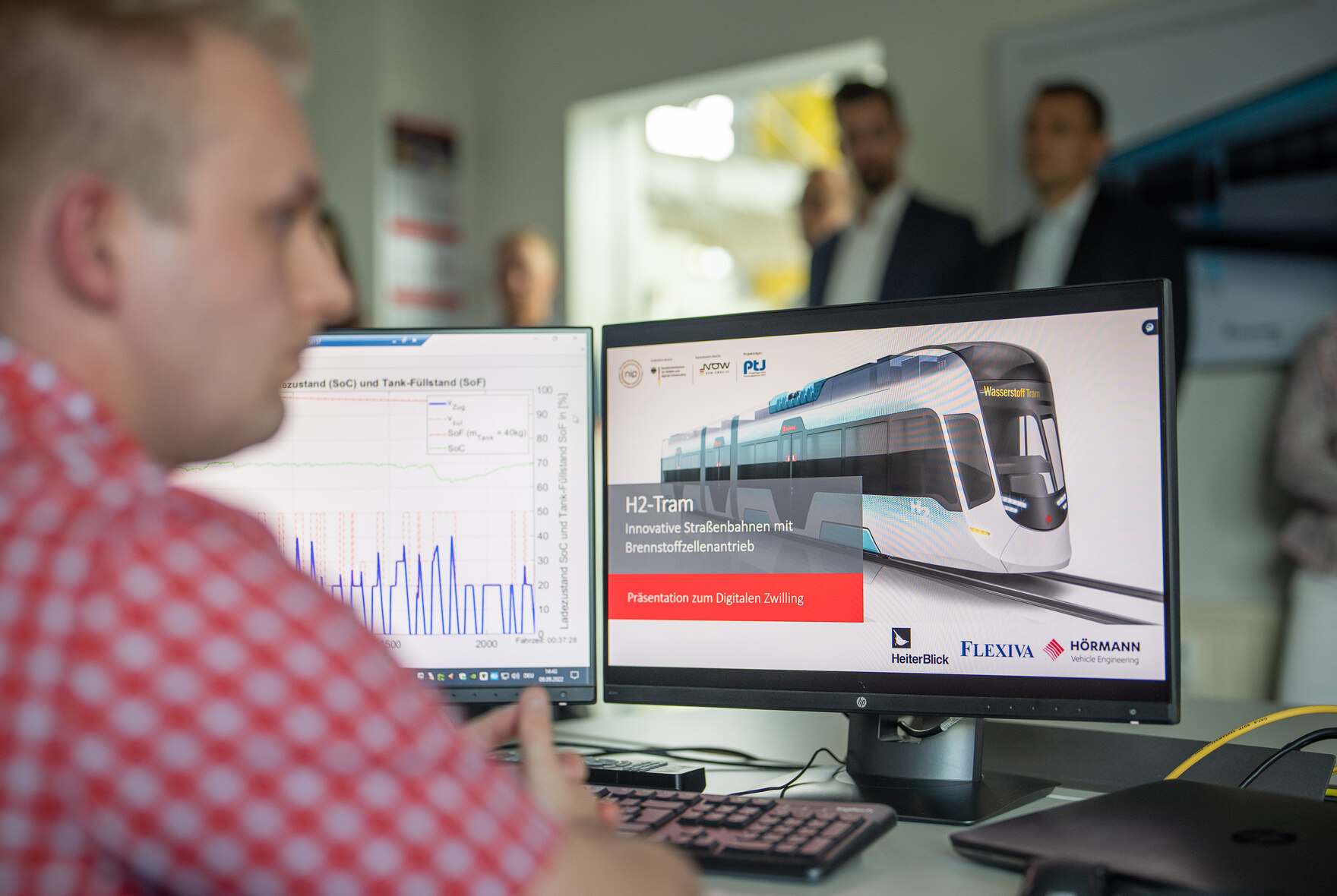 Ein Mitarbeiter arbeitet am Rechner. Auf dem Bildschirm ist eine Straßenbahn zu sehen.