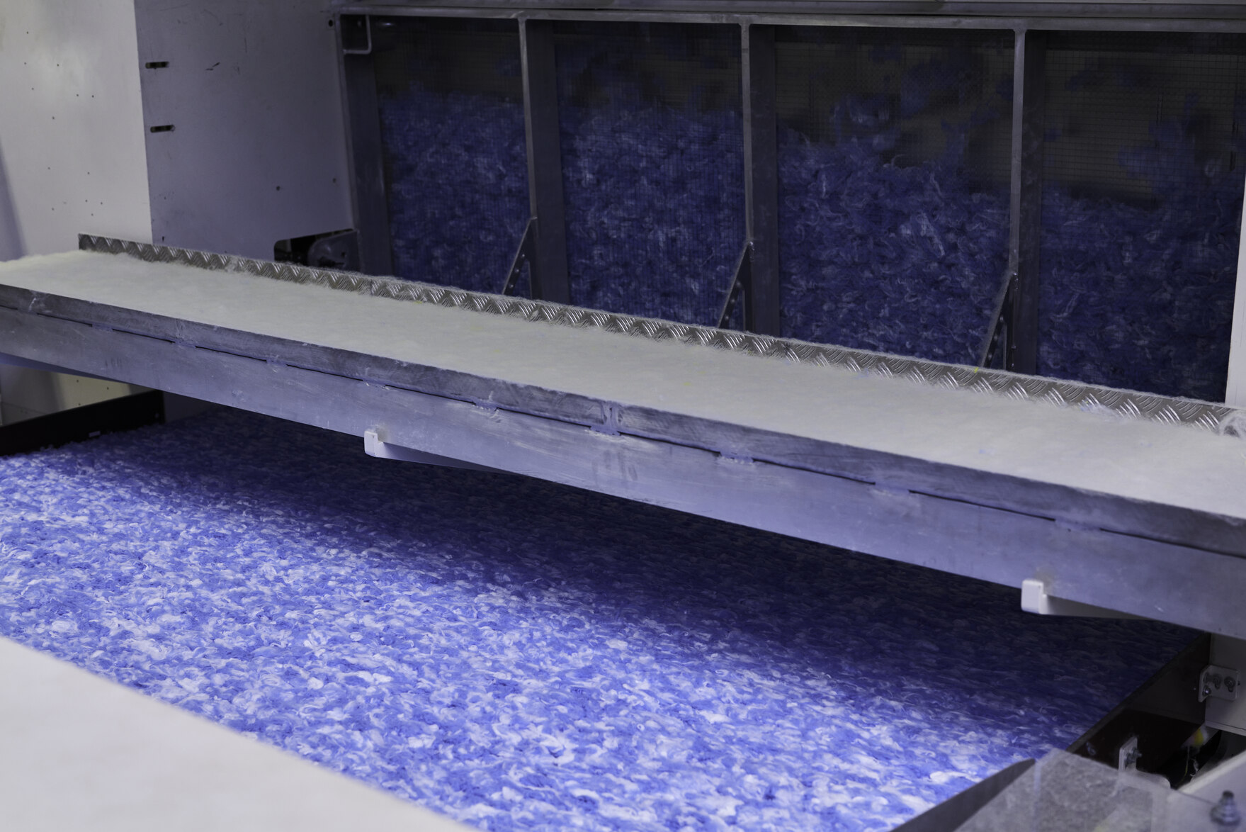Ein blauer Vliesstoff erscheint nach der Herstellung aus einer Maschine.