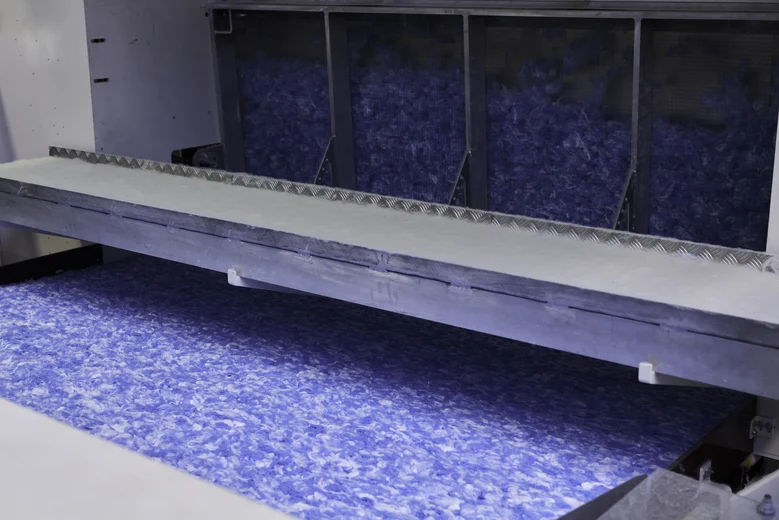 Ein blauer Vliesstoff erscheint nach der Herstellung aus einer Maschine.